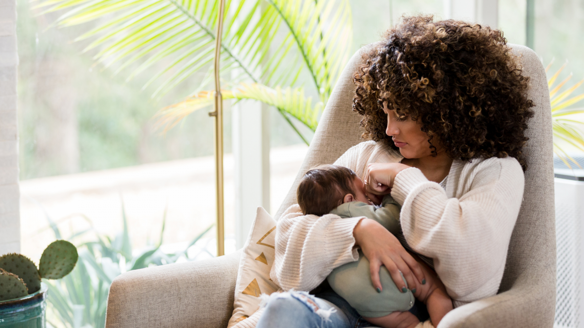 A woman of color cradling her baby in a chair