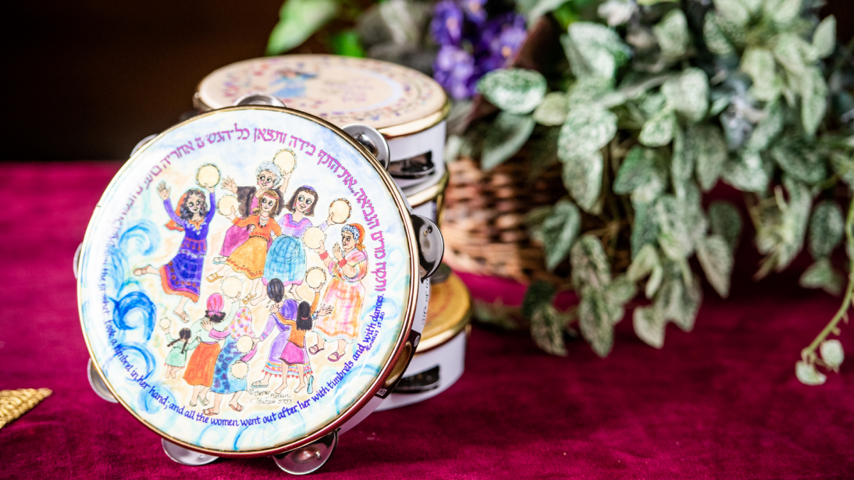 A tambourine painted with a dancing scene and Hebrew lettering