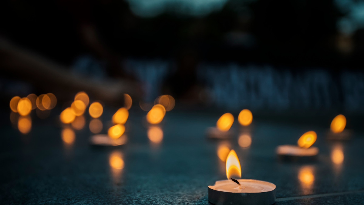 Lit tea lights on a dark surface.