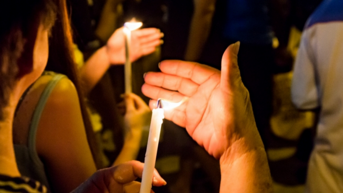 People holding lit candles at a vigil