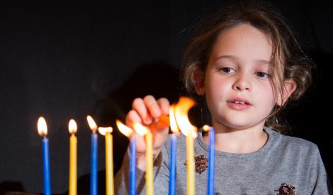 Girl lighting Hanukkah candles
