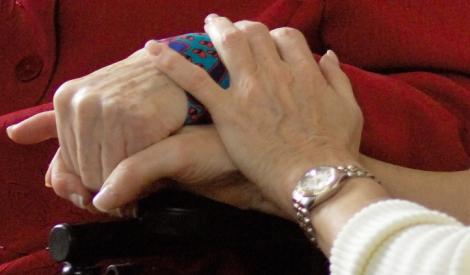 Bedside scene - chaplain holding hand of person in red coat