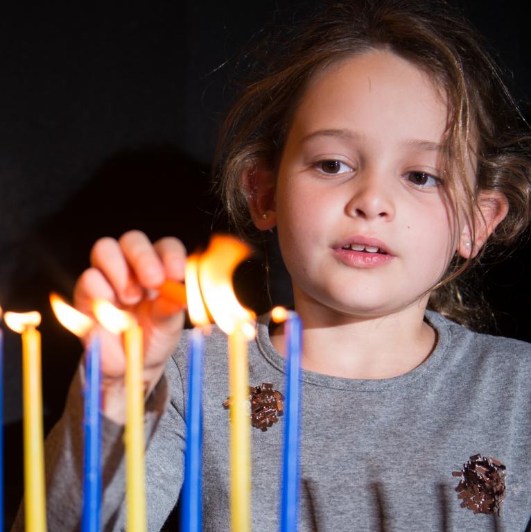Girl lighting Hanukkah candles