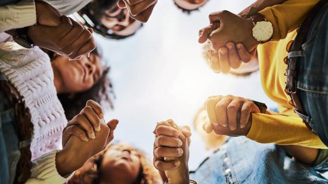 racially diverse group holding hands in a circle, viewed from below