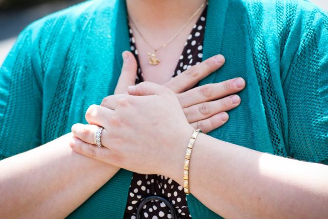 torso of person with hands clasped against chest