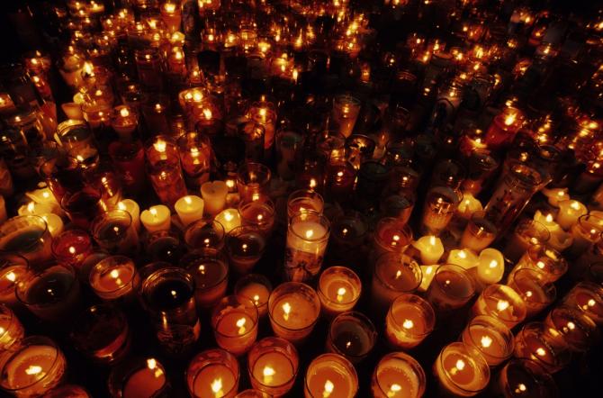 hundreds of yahrzeit candles, most burning, some extinguished, a few overturned