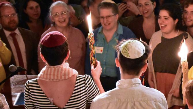 singing group in circle with havdalah candle