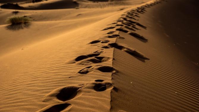 footsteps proceeding along top of sand dune in desert
