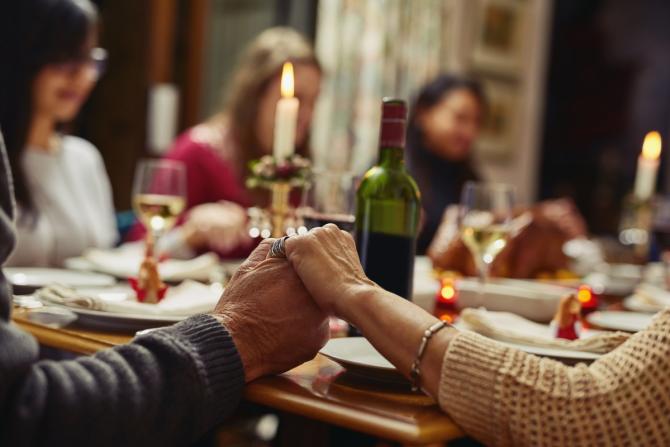 group holding hands around Shabbat table with candles and wine visible