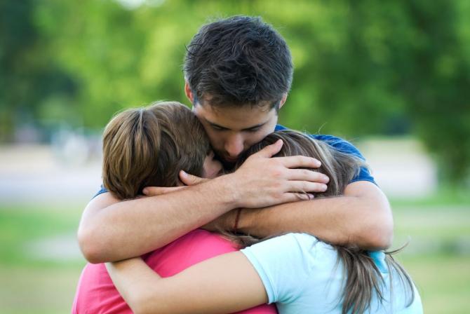 man hugging two children