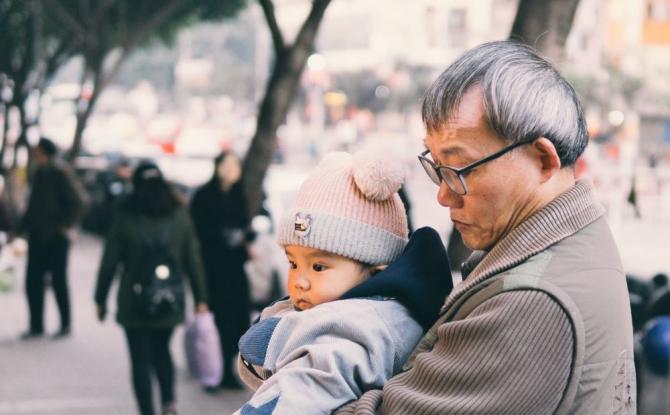 gray-haired man holding bundled-up toddler