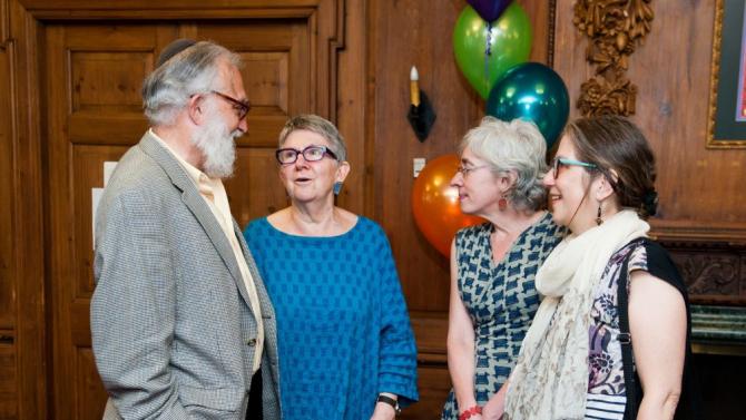 Four people standing close to one another in conversation