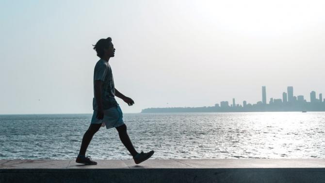 person walking on beach with cityscape in distance