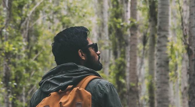 man gazing into the distance of a wooded area