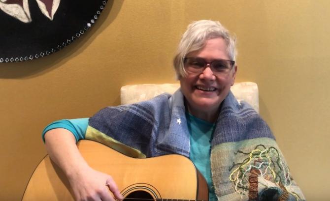 woman in tallit playing guitar