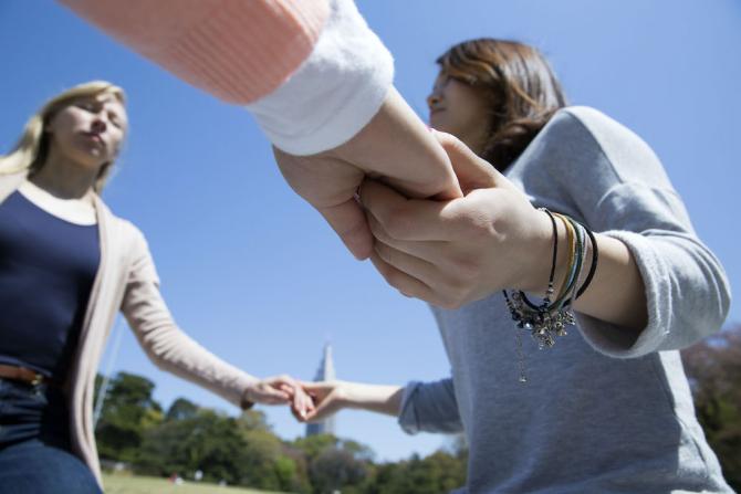 three women holding hands, seemingly part of a ring of people