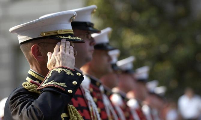 row of soldiers in dress uniforms saluting