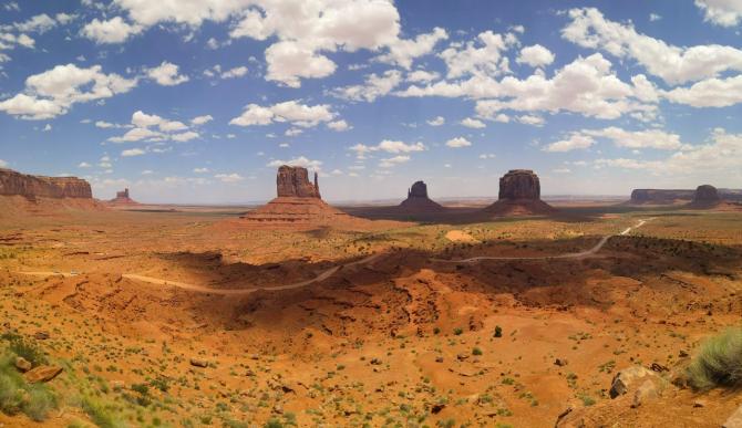 cliffs and mesas in the distance under a blue cloud-dotted sky