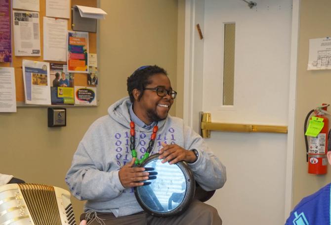 Koach Baruch Frazier plays a drum and laughs