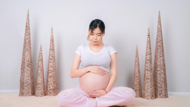 A pregnant woman cradling her exposed belly