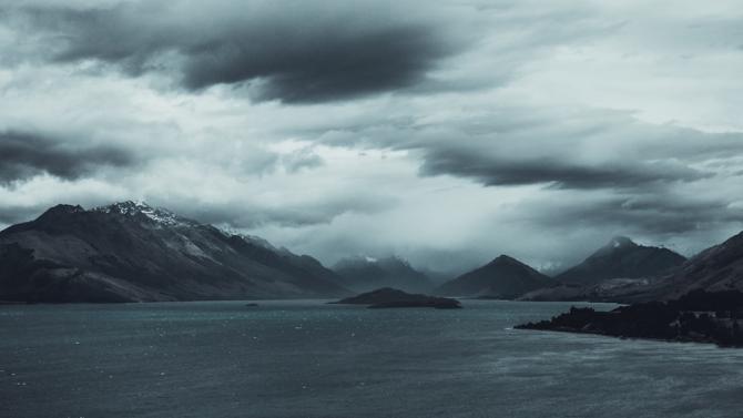 rocky mountainous shoreline under storm-clouded skies