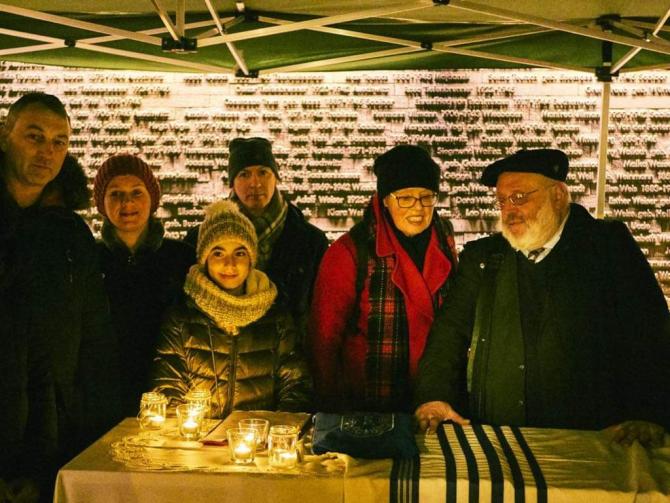 Group assembled around Torah scroll by candlelight