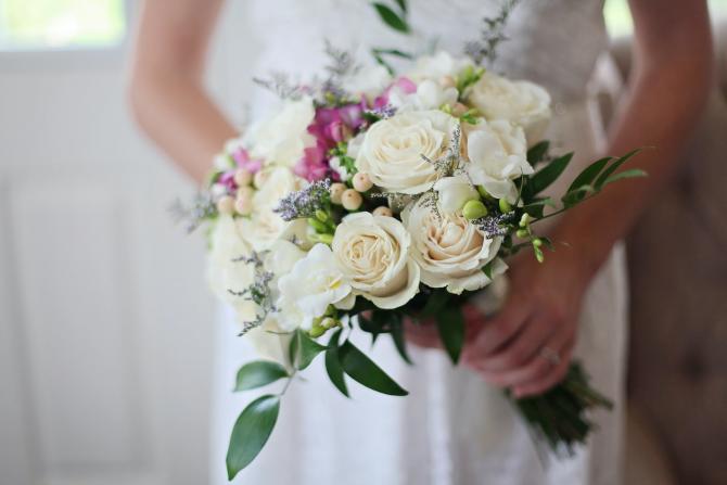 Bride in wedding dress holding bouquet, head and face not visible
