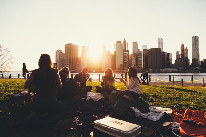 sunset over Manhattan viewed from a park in Brooklyn - figures visible at a picnic table in silhouette