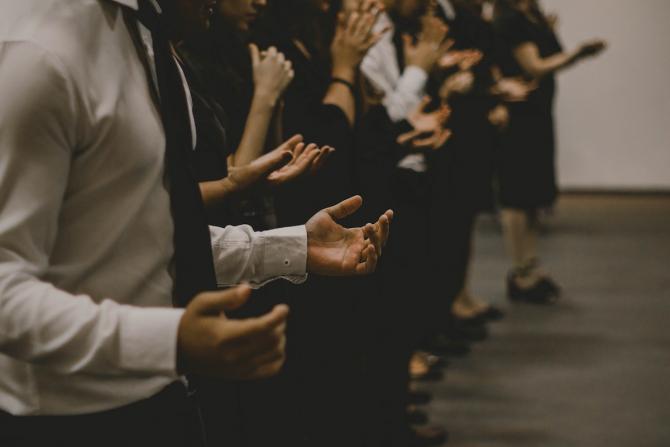 Hands and bodies of a row of people standing in prayer