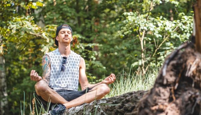 Man meditating while sitting cross-legged in the woods