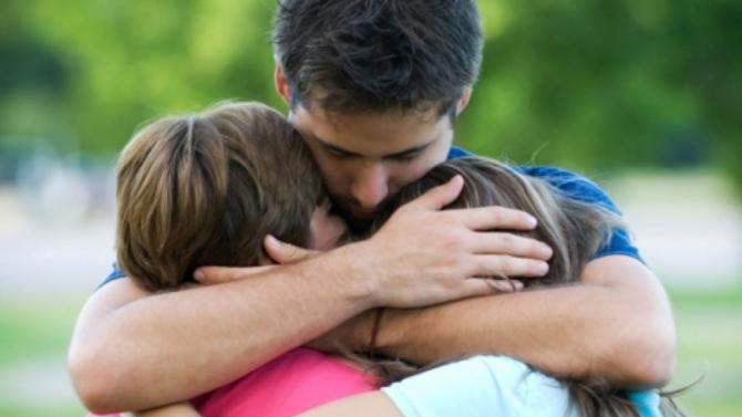 father hugging children