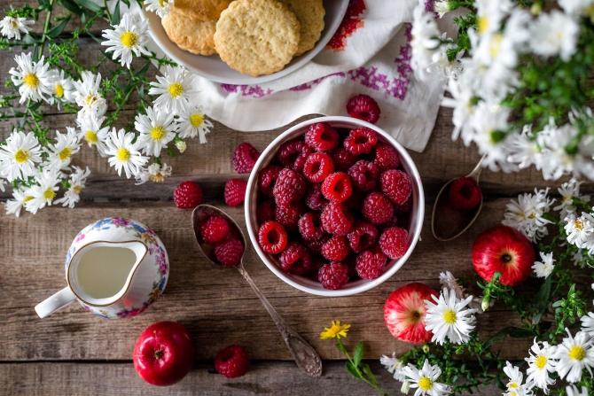 Table filled with berries, cream and flowers