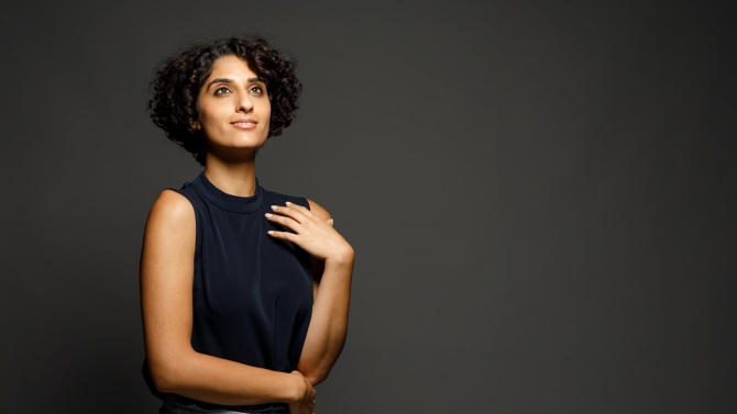 Woman with curly hair in front of a dark background