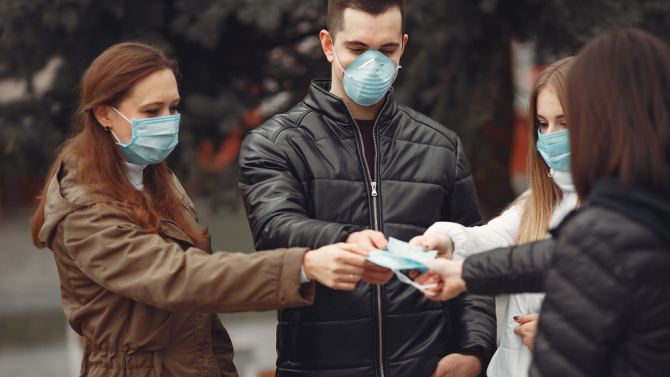 Four people holding one face mask togther