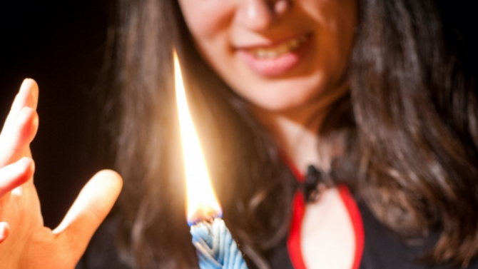A woman with dark hair behind a Havdalah candle