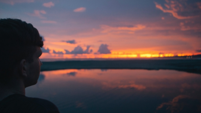 Person looking out onto a body of water at sunrise