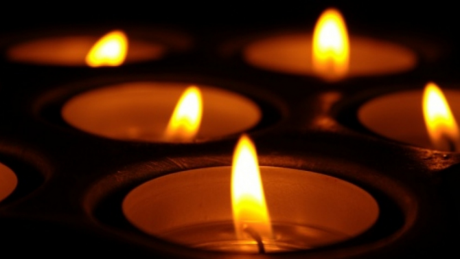 Close up on several lit candles shining in the dark