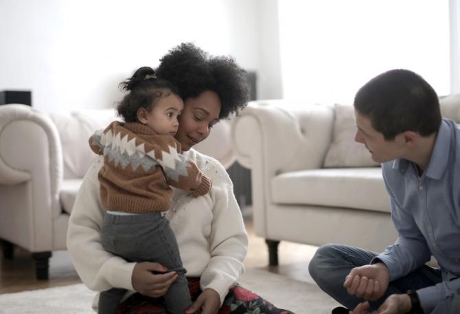 father talking to toddler held by mother