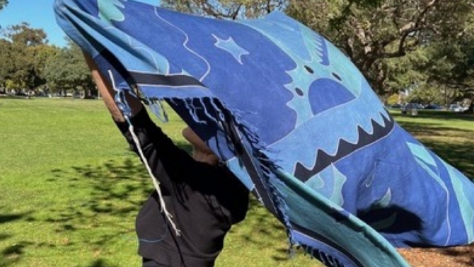 Woman holding up a patterned blue shawl