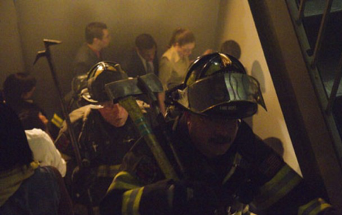 Crowded stairwell with firefighters in full gear climbing toward the photographer