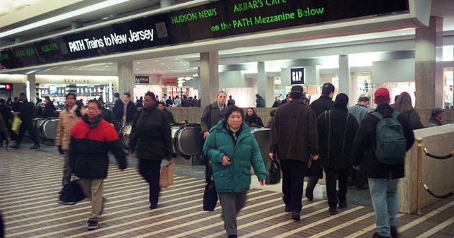 Busy underground train terminal with passengers entering and exiting escalators to the track level