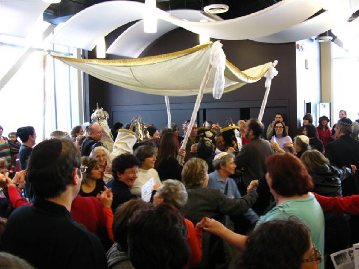 Crowd dancing around wedding canopy