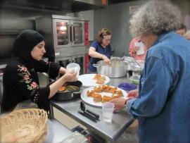 Afghani woman in traditional garb preparing food alongside students