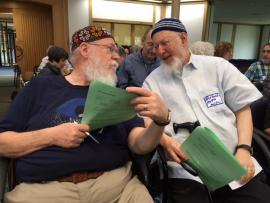 Two men in conversation amidst crowd of adult learners