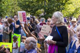 Outdoor demonstration with crowd holding signs in support of refugees