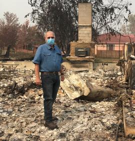 Man in face mask standing in burnt ruins of a house