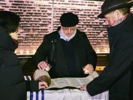 Man standing over Torah scroll with Yahrzeit candles