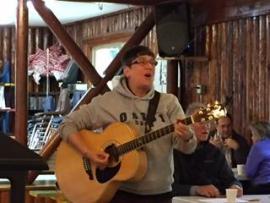 Person playing guitar and wearing a sweatshirt