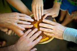 Hand surround a challah, touching it to bless it