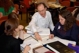 Talmud students at table with books, Rabbi Eli Kaunfer teaching